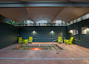 Thumbnail 3 of 51 - A hot tub is surrounded by four chairs in a room with a black wall.