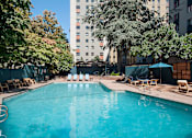 Thumbnail 2 of 51 - A swimming pool surrounded by trees and chairs.