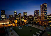 Thumbnail 1 of 51 - A cityscape at night with a green space in the foreground.