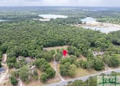 Thumbnail 4 of 8 - An aerial view of a lush green forest with a red pin marking a specific location.