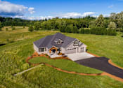 Thumbnail 6 of 8 - A house with a grey roof and a driveway in front of it.