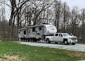 Thumbnail 2 of 8 - A white RV is being towed by a white pickup truck.