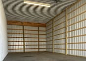 Thumbnail 7 of 13 - A large, empty garage with a concrete floor and a metal wall.