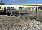Thumbnail 2 of 13 - A metal gate blocks the entrance to a gravel lot.
