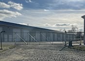 Thumbnail 3 of 13 - A gravel area in front of a fenced building.