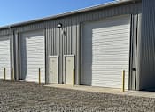 Thumbnail 4 of 13 - A building with grey walls and white roller doors.