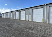 Thumbnail 1 of 13 - A long row of storage units with closed grey doors.