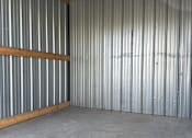 Thumbnail 7 of 10 - A large empty room with a grey floor and a corrugated metal wall.