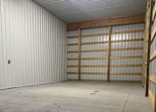 Thumbnail 8 of 10 - A large, empty garage with a white interior and a concrete floor.