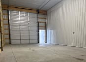 Thumbnail 9 of 10 - A large, empty warehouse with a closed metal door in the center.