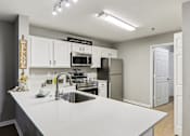Thumbnail 23 of 33 - A kitchen with a white countertop and a sign that says "welcome".