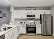 Thumbnail 21 of 33 - A kitchen with a stove top oven and a refrigerator.