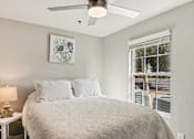 Thumbnail 19 of 33 - A bedroom with a bed, a lamp, and a ceiling fan.