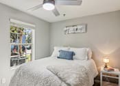 Thumbnail 17 of 33 - A bedroom with a bed, a ceiling fan, and a window with a view of a parking lot.