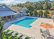 Thumbnail 2 of 33 - A large outdoor swimming pool surrounded by lounge chairs and umbrellas.