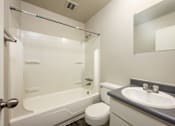Thumbnail 25 of 31 - A white bathroom with a toilet, sink, and bathtub.