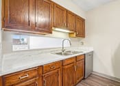 Thumbnail 12 of 22 - Irvine Park Towers kitchen with wood cabinets, light countertops, sink and dishwasher
