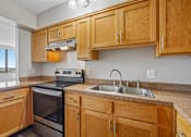 Thumbnail 15 of 22 - Irvine Park Towers kitchen with wood cabinets, double sink, range and window