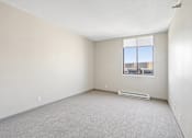 Thumbnail 17 of 22 - Irvine Park Towers apartment bedroom with carpeted flooring, neutral walls and large window