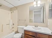 Thumbnail 20 of 22 - Irvine Park Towers apartment bathroom with wood vanity, large mirror and tub-shower combination