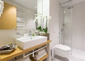 Thumbnail 4 of 7 - A modern bathroom with a white sink and a glass shower stall.