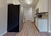 Thumbnail 2 of 20 - A black refrigerator is in the corner of a kitchen with wood flooring. at Spalding Vue, Peachtree Corners, 30092