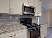Thumbnail 1 of 20 - A kitchen with a black stove top oven and a microwave above it. at Spalding Vue, Peachtree Corners, 30092