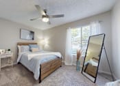 Thumbnail 7 of 26 - A bedroom with a bed, nightstand, and a ceiling fan.