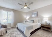 Thumbnail 10 of 26 - A bedroom with a bed, chair, and a ceiling fan.