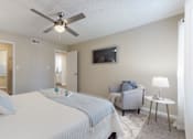 Thumbnail 12 of 26 - A bedroom with a bed, chair, and ceiling fan.