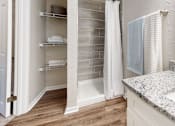 Thumbnail 11 of 26 - A bathroom with a marble countertop and a walk-in shower.