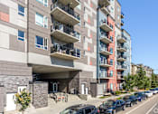 Thumbnail 47 of 72 - A modern apartment building with cars parked in front.
