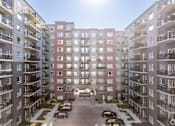 Thumbnail 46 of 72 - A sunny day at a residential apartment complex with cars parked in the driveway.