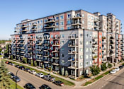 Thumbnail 48 of 72 - A large apartment building with many balconies and cars parked in front.