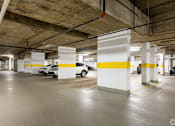 Thumbnail 58 of 72 - A parking garage with white and yellow pillars and cars parked in it.