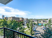 Thumbnail 44 of 72 - A balcony overlooks a parking lot and buildings.