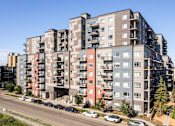 Thumbnail 66 of 72 - A large apartment building with cars parked in front.