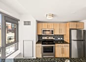 Thumbnail 13 of 29 - A kitchen with wooden cabinets and a black stove top oven.