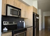 Thumbnail 14 of 29 - A kitchen with wooden cabinets and black appliances.at 66 Main, Yonkers, NY 10701