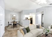 Thumbnail 1 of 17 - A living room with a white couch and a dining table with chairs.