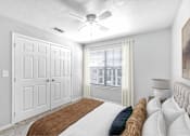 Thumbnail 3 of 17 - A bedroom with a bed, a ceiling fan, and a window with curtains.