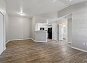 Thumbnail 4 of 17 - A spacious room with wood flooring and a kitchenette in the background.