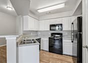 Thumbnail 5 of 17 - A kitchen with black appliances and white cabinets.