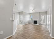 Thumbnail 6 of 17 - A spacious living room with wood flooring and a fireplace.