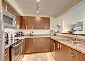 Thumbnail 7 of 18 - A kitchen with wooden cabinets and a granite countertop. at Mill Creek Meadows Apartments, Washington, 98012