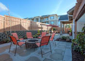 Thumbnail 3 of 18 - A patio with a table and chairs is surrounded by a wooden fence. at Mill Creek Meadows Apartments, Mill Creek, WA