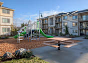 Thumbnail 2 of 18 - A playground with a green slide and a picnic table in front of apartment buildings. at Mill Creek Meadows Apartments, Mill Creek