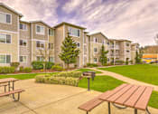 Thumbnail 4 of 19 - Apartment complex with a grassy area and picnic tables in front at Valley Springs Apartments, Renton