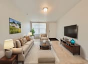 Thumbnail 3 of 6 - A living room with a beige sofa, a coffee table, and a flat screen TV mounted on the wall.
