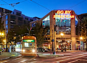 Thumbnail 29 of 29 - A streetcar is passing by a building with a neon sign that says "GO BY STREETCAR".